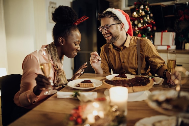 Happy couple laughing while talking during Christmas dinner at home