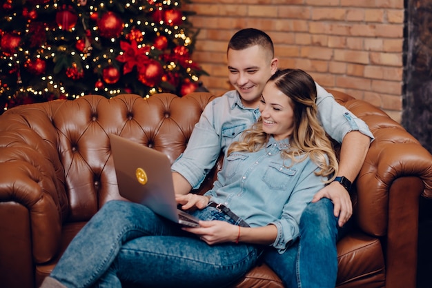 Happy couple looking at laptop monitor on of Christmas decorations