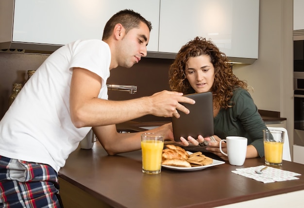 家の朝食でタブレットを探している幸せなカップル