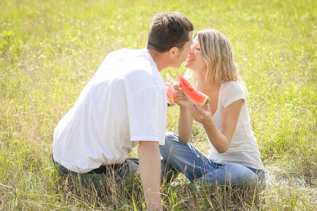 Foto coppia felice innamorata che mangia cocomeri all'aperto nel parco estivo