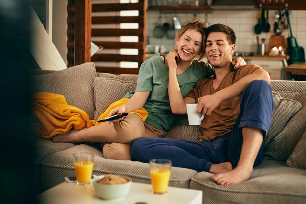 Happy couple in love enjoying while watching TV at home