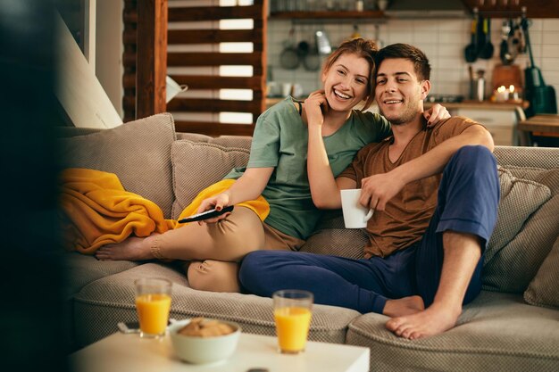 Felice coppia innamorata godendo mentre si guarda la tv a casa