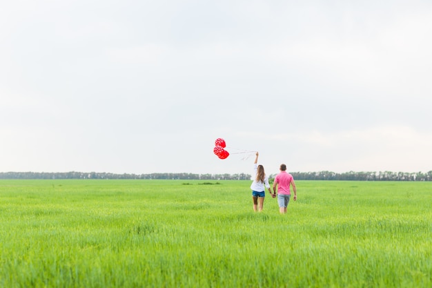 Happy couple in love holding red balloon, back view