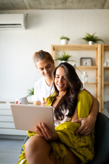 Photo happy couple in love hugging and using tablet together at home