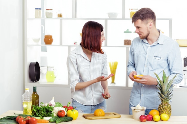 Happy couple in love in the kitchen making a healthy juice from fresh orange