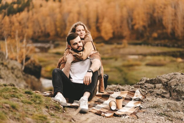 Photo a happy couple in love a man and a woman are traveling walking hiking in the autumn forest in nature