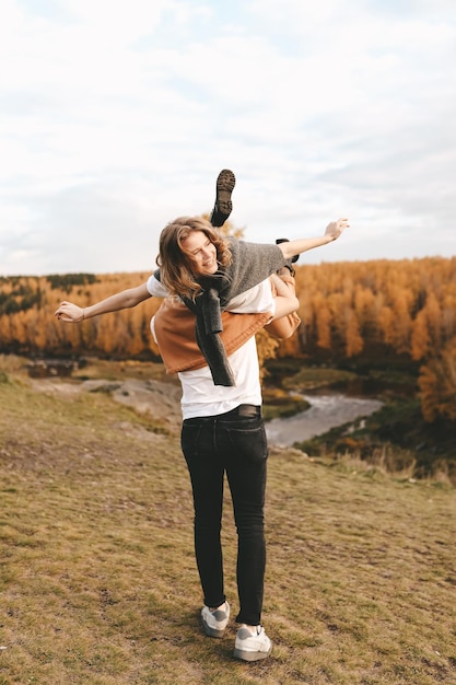 a happy couple in love a man and a woman are traveling walking hiking in the autumn forest in nature