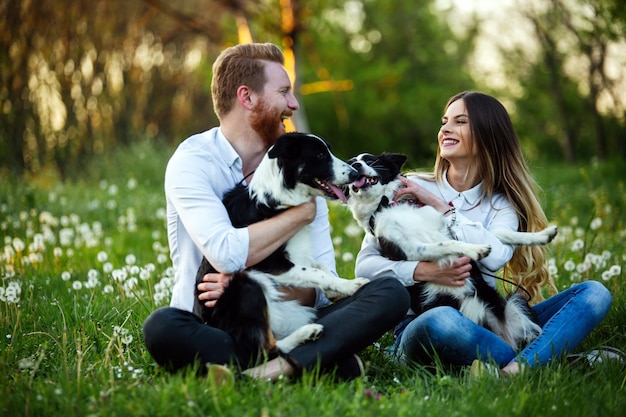 Счастливая влюбленная пара, играя с собаками в парке на открытом воздухе