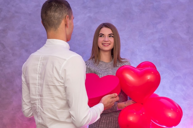 Happy couple in love posing with red air balloons in shape of heart