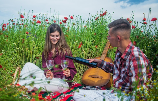 Happy couple in love relax in beautiful field of poppy flower with acoustic guitar music serenade