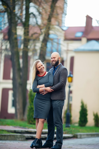 Счастливая пара в любви, улыбаясь, стоя на фоне здания