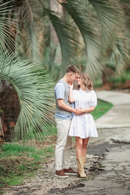 A happy couple in love walk in the Park under palm trees, holding hands.