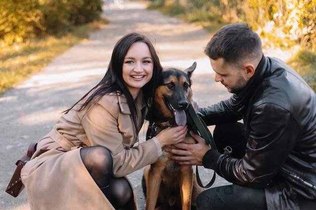 Photo a happy couple in love walks with a pet dog in an autumn outdoor nature park in fall