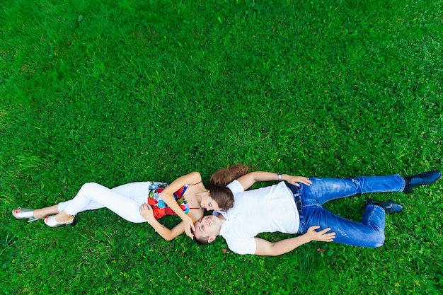 행복한 커플 연인들은 풀밭에 누워 있다 긴 검은 머리와 젊은 남자를 가진 아름다운 소녀