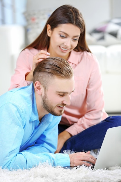 Coppia felice sdraiato sul pavimento e lavorando al computer portatile