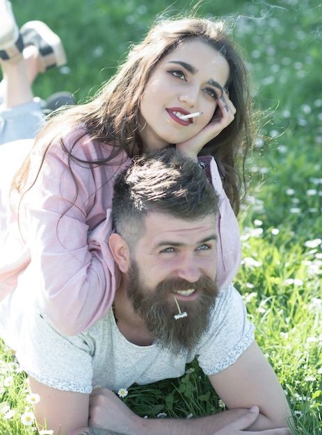 Happy couple lying on green grass meadow man enjoying sunny day with girlfriend outdoors spring time concept