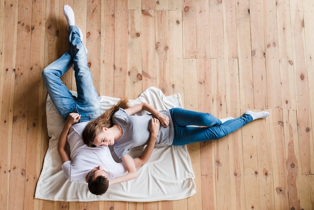 Photo happy couple lying on sheet on floor