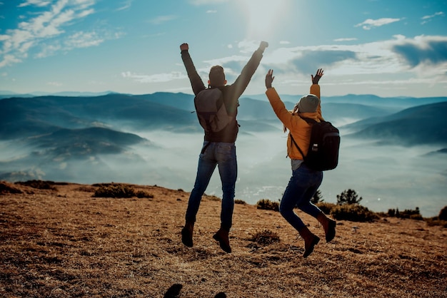 happy couple man and woman tourist at top of mountain during a hike in summer