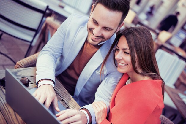 Happy couple meeting at cafe with laptop