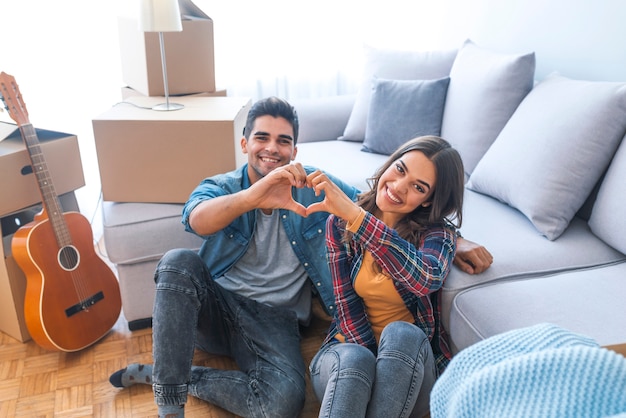 Happy couple during moving house showing heart sign