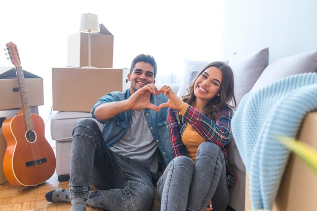 Happy couple during moving house showing heart sign