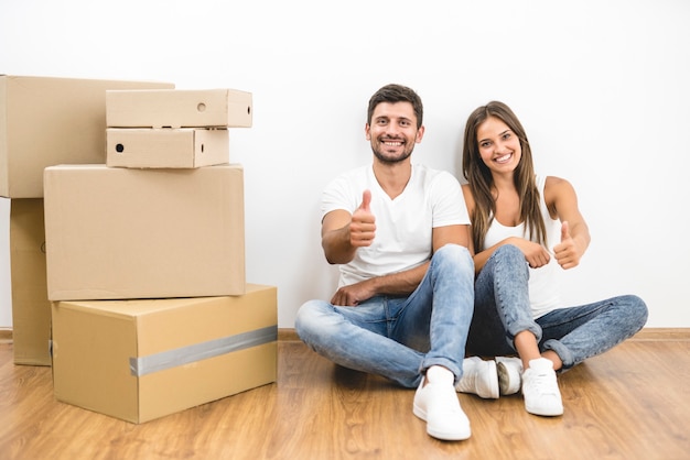 The happy couple moving to the new house and gesture near the white wall