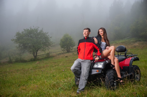 Photo happy couple near four-wheeler atv in foggy nature