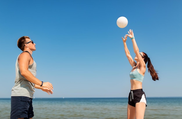 Happy couple playing volleyball on summer beach