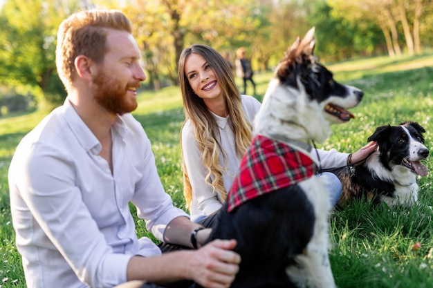 Happy couple playing with dog in the park outdoor. People, pet concept