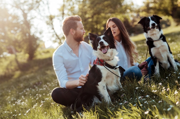 Photo happy couple playing with dog in the park outdoor. people, pet concept