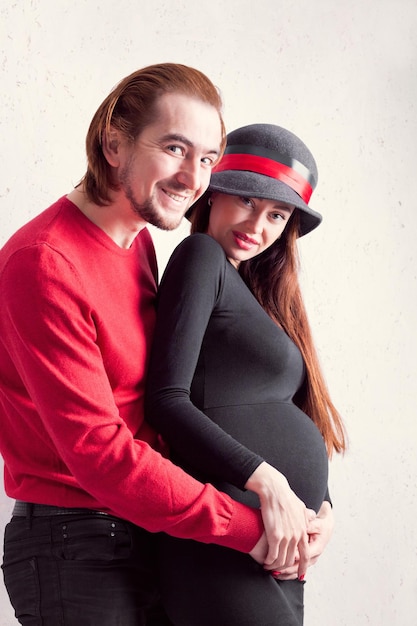 Happy couple of pregnant girl who stands with her husband and hold together herself tummy