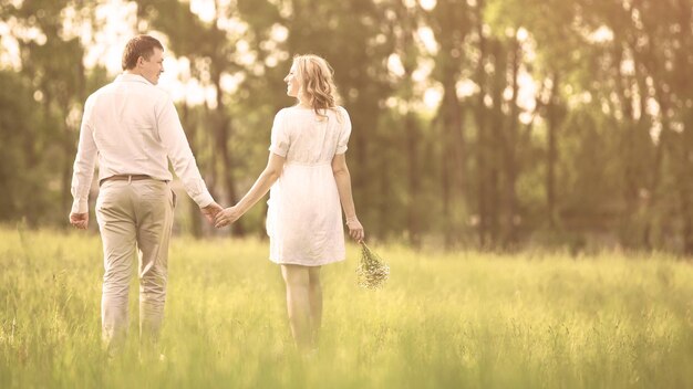 Happy couple pregnant woman and her husband go on a picnic the grass