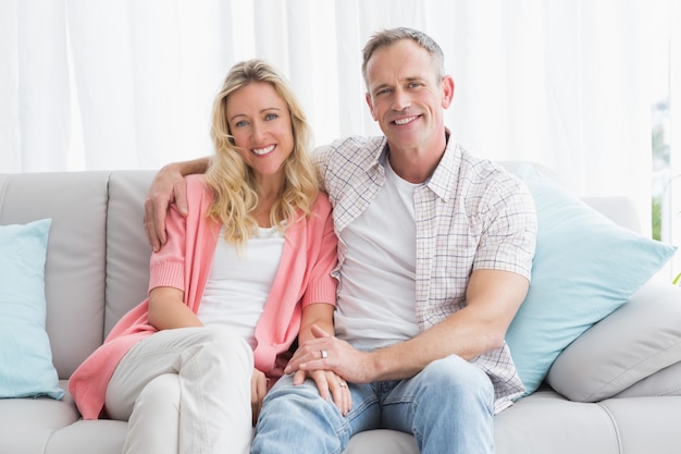 Happy couple relaxing on the couch smiling at camera