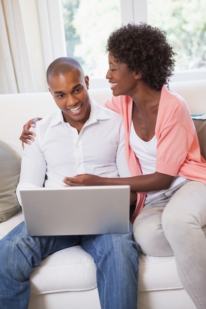 Happy couple relaxing on the couch with laptop