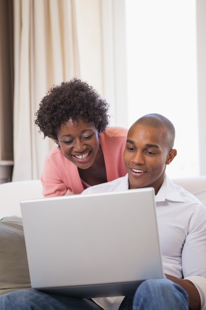 Happy couple relaxing on the couch with laptop