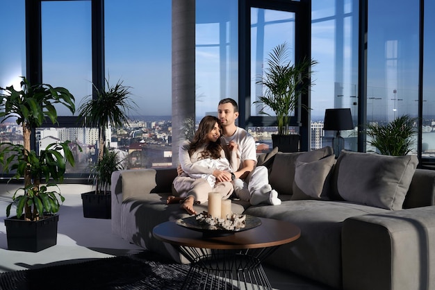 Happy couple resting at home near panoramic window