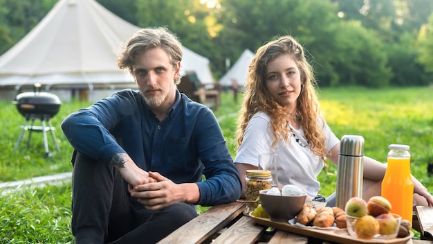 Una coppia felice che riposa nella natura al glamping. bevande e cibo, verde intorno