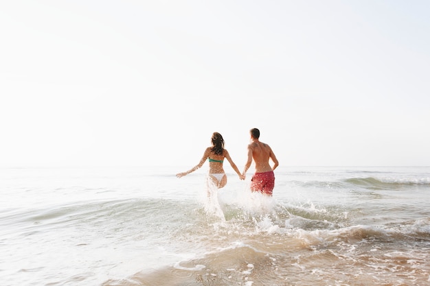 Happy couple running into the water