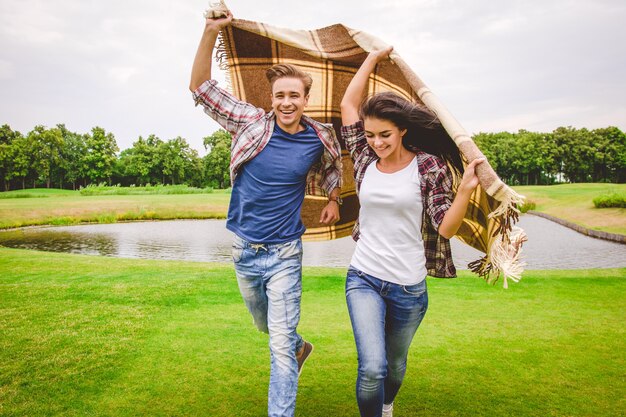 The happy couple running near the lake