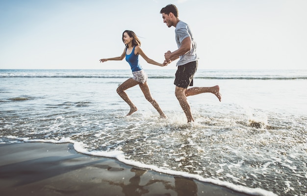 Счастливая пара бежит по берегу