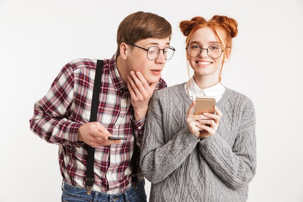 Happy couple of school nerds using mobile phones