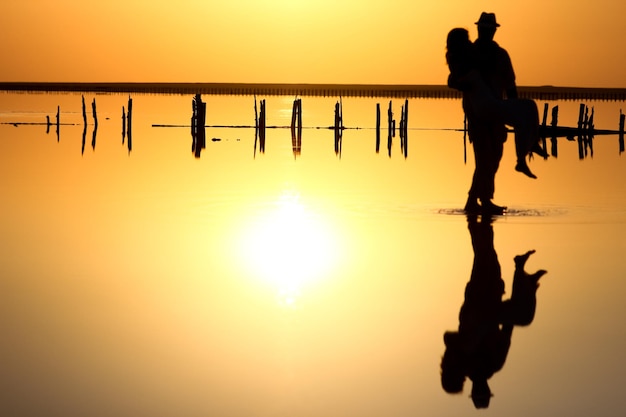 A happy couple at sea with water reflection silhouette background