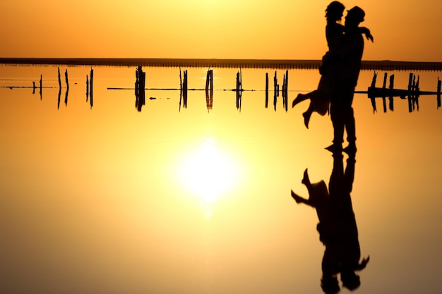 Photo a happy couple at sea with water reflection silhouette background