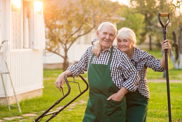 Happy couple of senior gardeners man and woman outdoor background