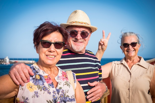 Happy couple of senior people with a female friend enjoy sea excursion in summer vacation