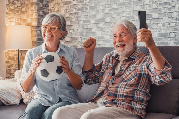 Happy couple of seniors or football fans watching soccer on tv
and celebrating victory at home family sports and entertainment
conceptxa