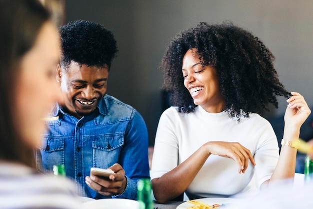 Счастливая пара делит мобильный телефон за обеденным столом