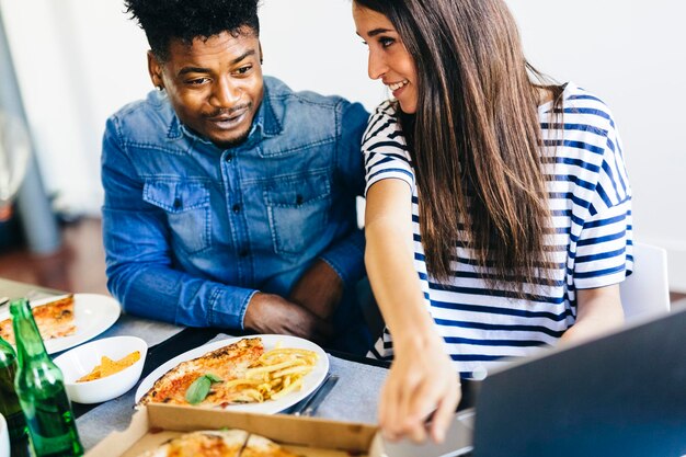 Happy couple sharing laptop at dining table