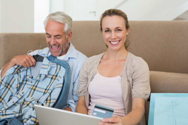 Happy couple shopping online on the couch at home in the living room