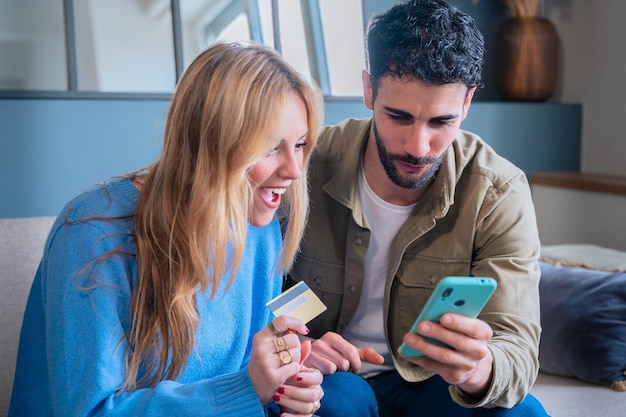 happy couple shopping online with credit card and smartphone smiling at screen